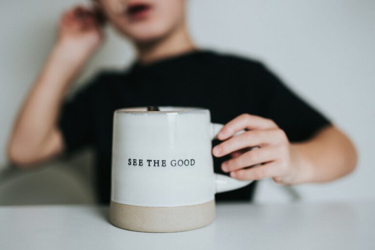 child holding mug with see the good text written on it