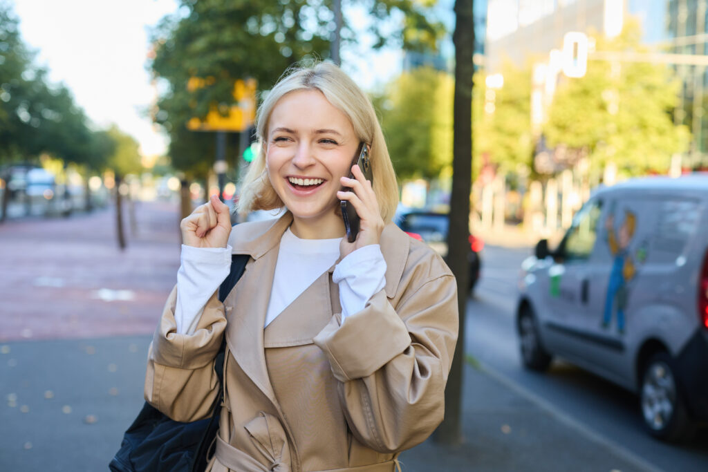 portrait cheerful woman talking mobile phone while walking along London street